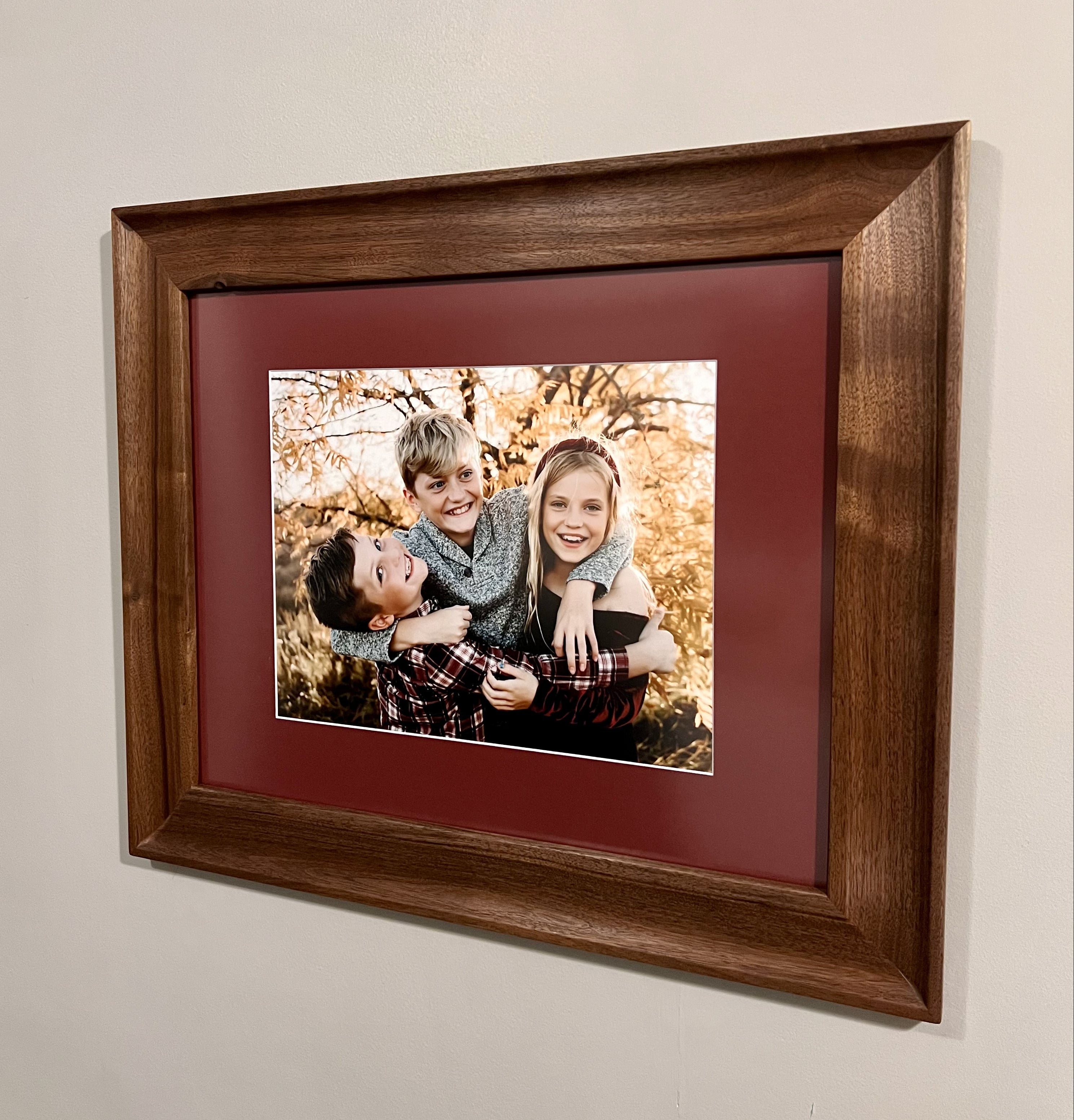 Framed photograph of a family in a wooden frame on a beige wall